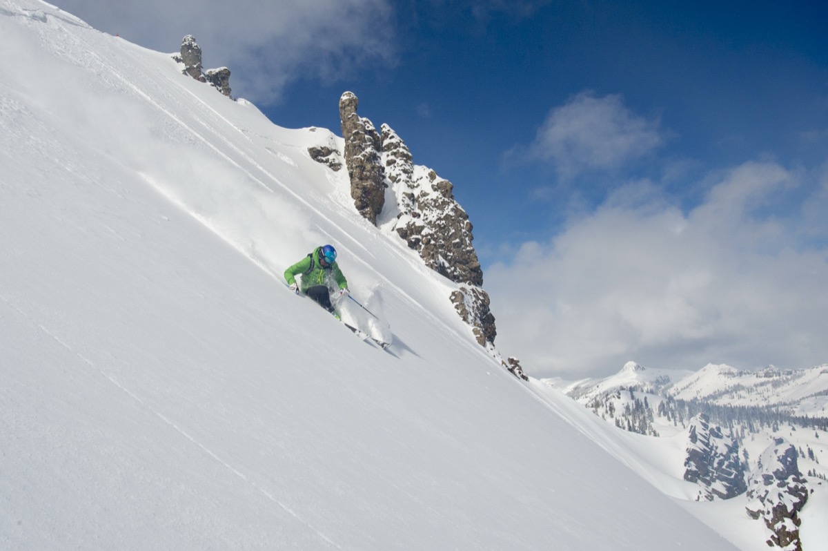 Errol skiing steep powder in the Sierra backcountry with rock formations behind him