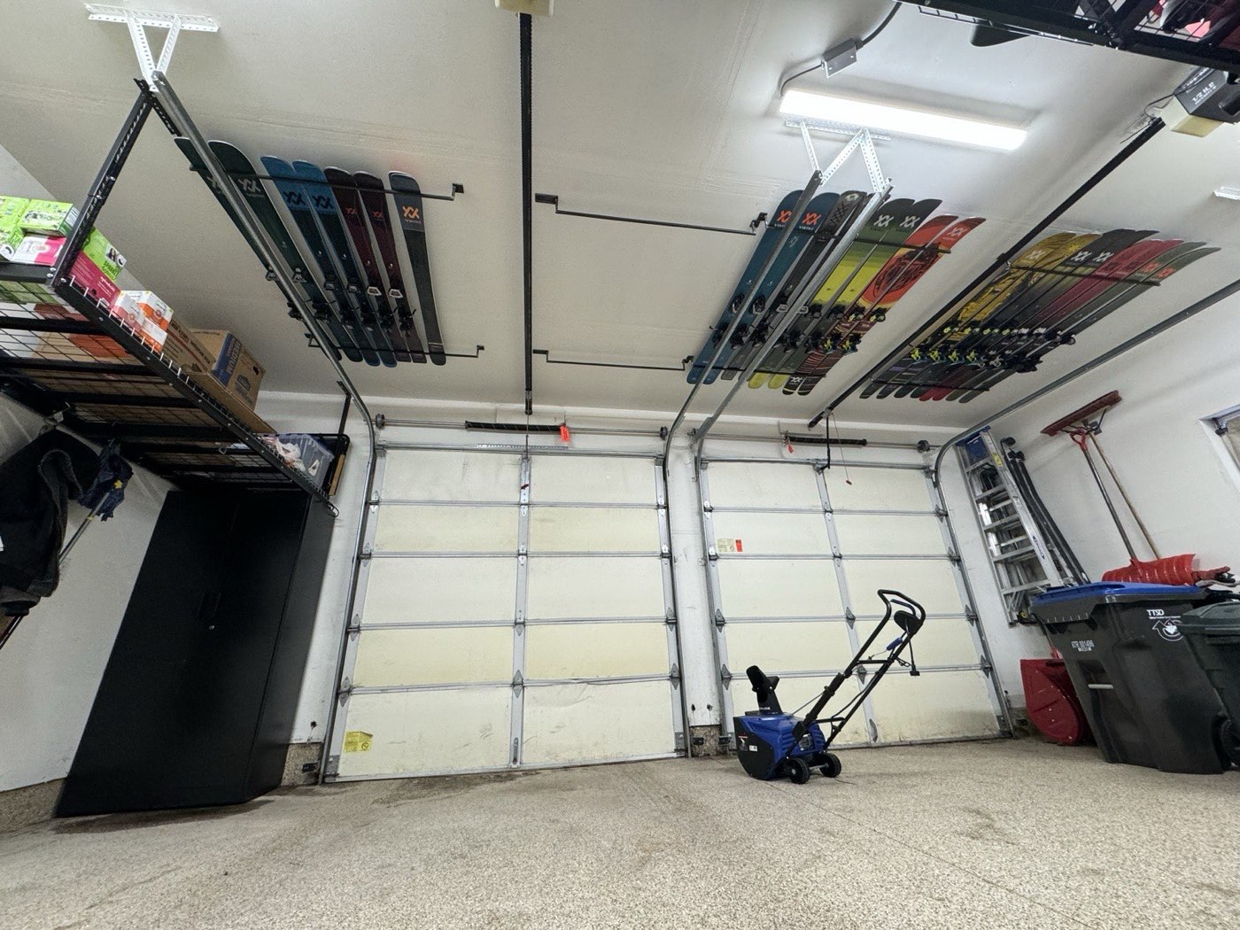 Skis stored on ceiling racks above both closed garage doors
